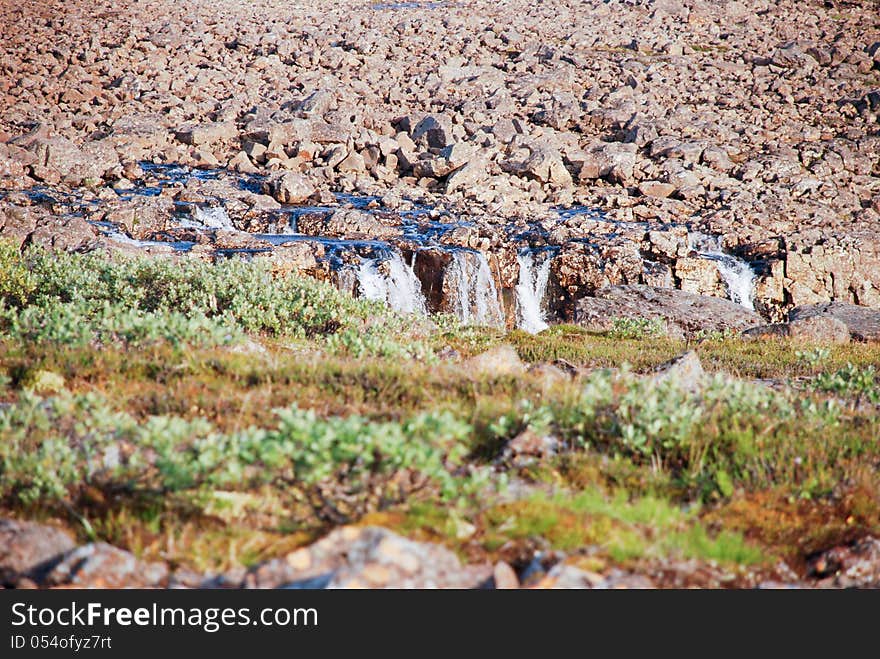 A Rocky Landscape With A Waterfall.