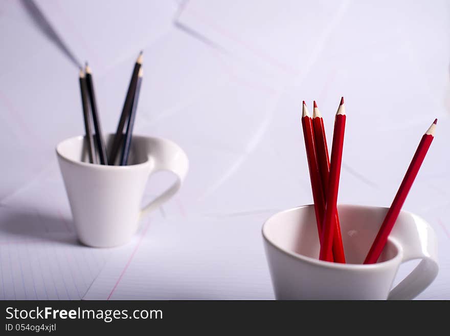 Black and red pencils stand in two cups