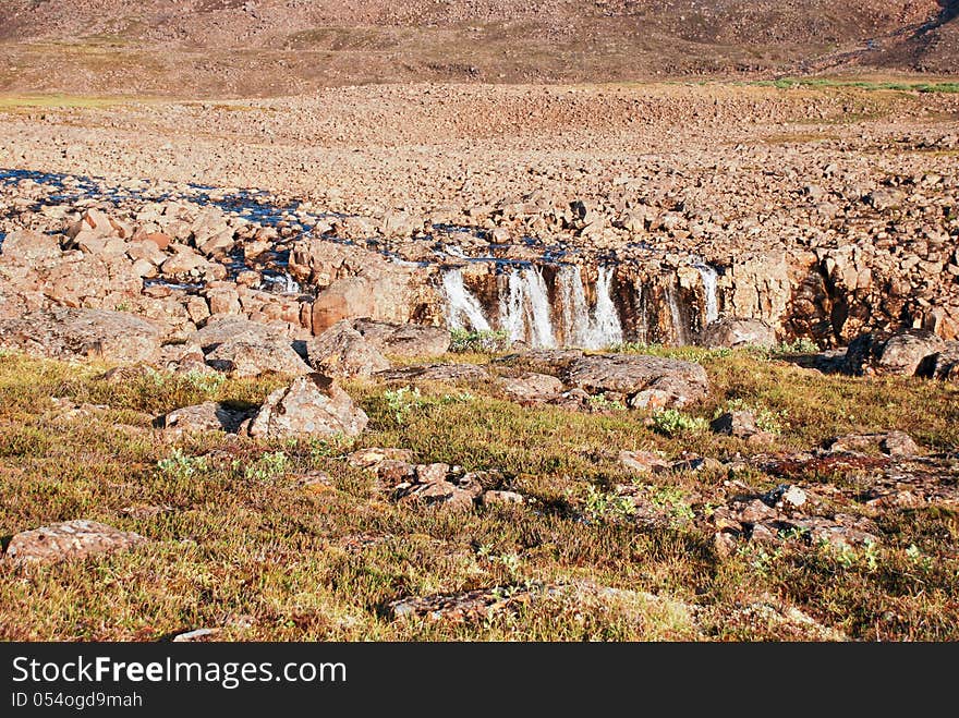 A Rocky Landscape With A Waterfall.