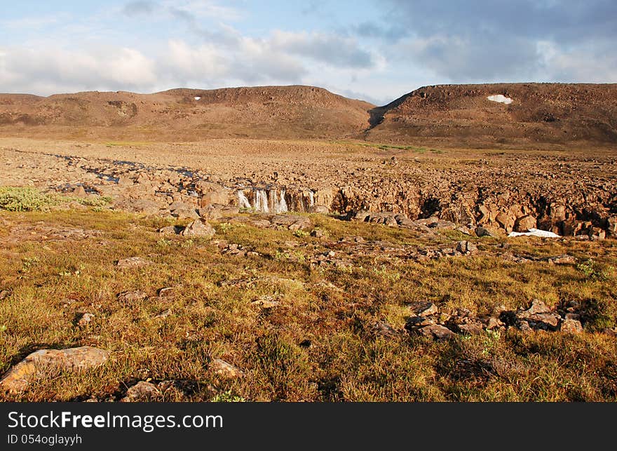 A Rocky Landscape With A Waterfall.