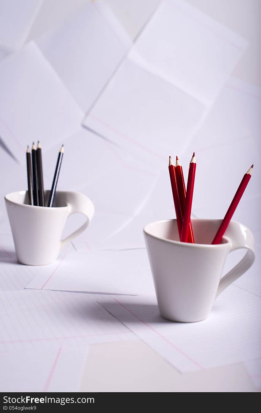 Black and red pencils stand in two white cups