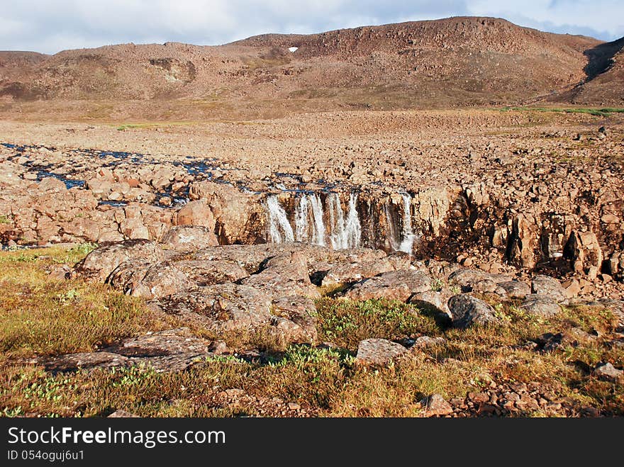 A Rocky Landscape With A Waterfall.