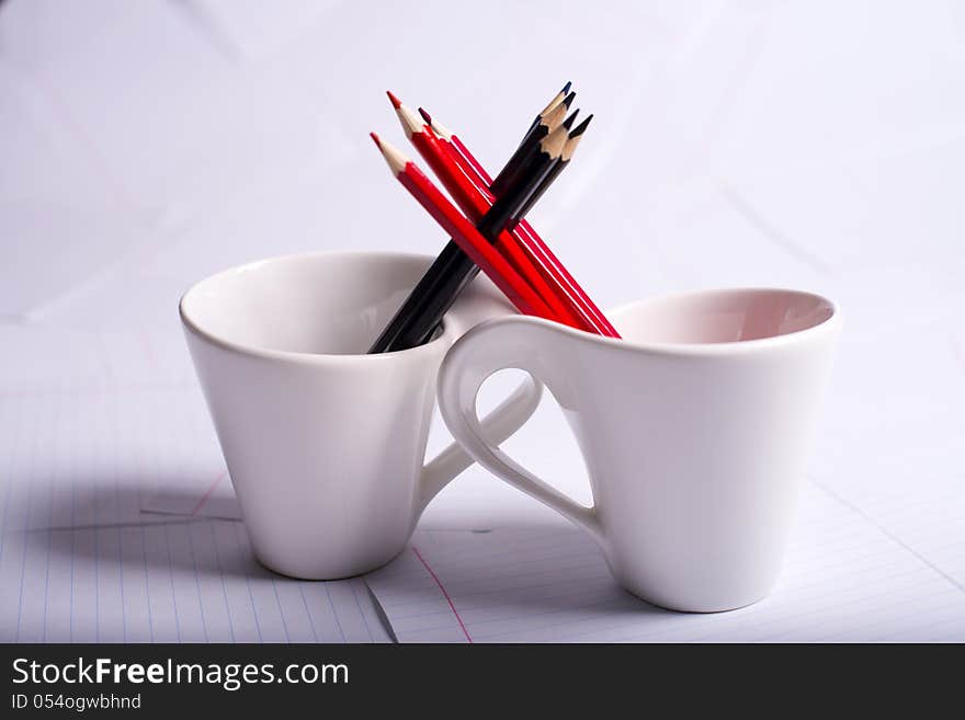 Black and red pencils stand in two cups