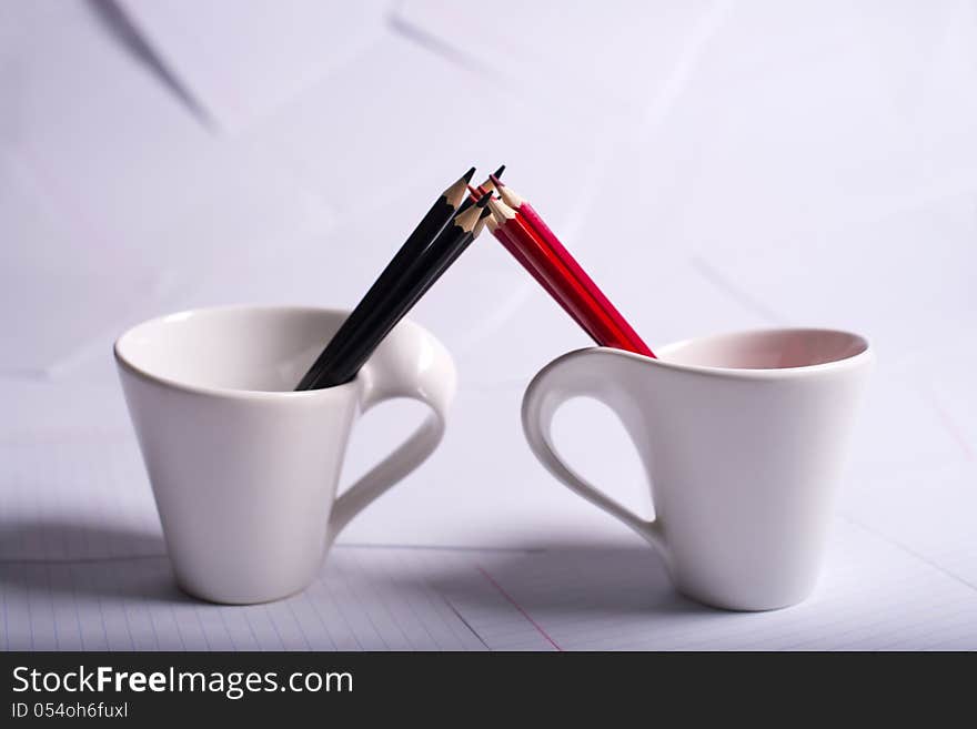 Black and red pencils stand in two cups