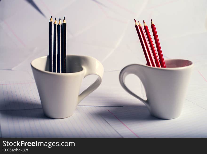 Black and red pencils stand in two white cups