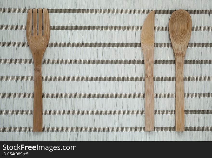 Wooden eating utensils:fork,knife and spoon on white background with horizontal stripes. Wooden eating utensils:fork,knife and spoon on white background with horizontal stripes