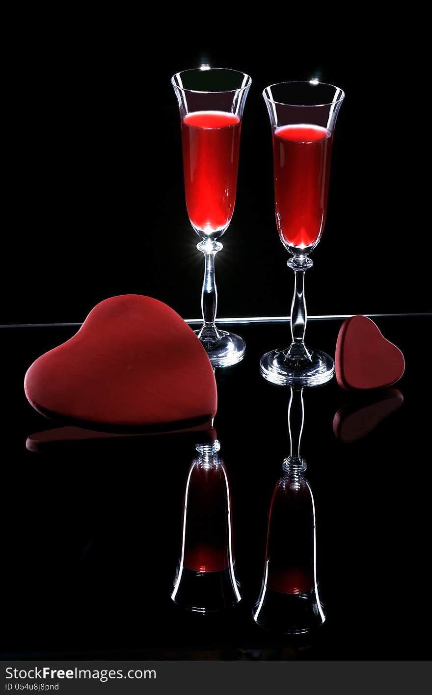 Two wine glasses and hearts on a dark background