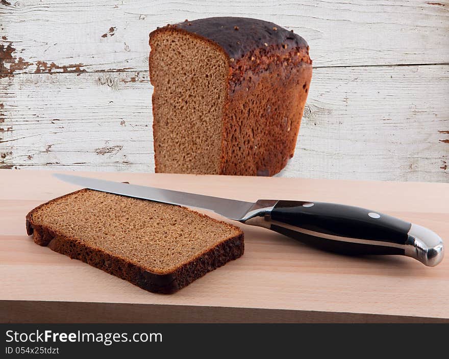 Knife and chopped rye bread on cutting board wooden