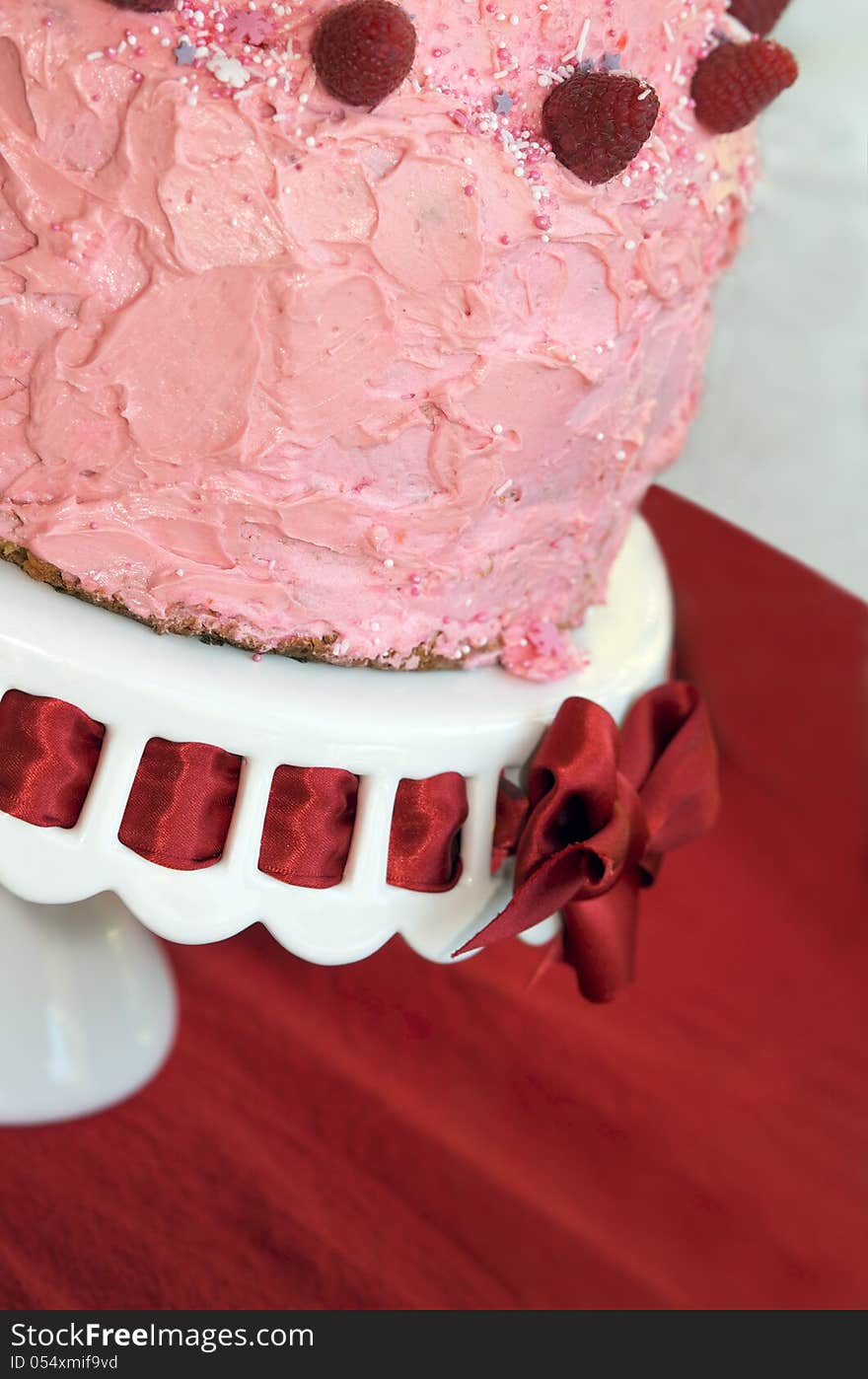 Pink birthday party cake for girl with red ribbon cake stand and fairy dust sprinkles. Pink birthday party cake for girl with red ribbon cake stand and fairy dust sprinkles