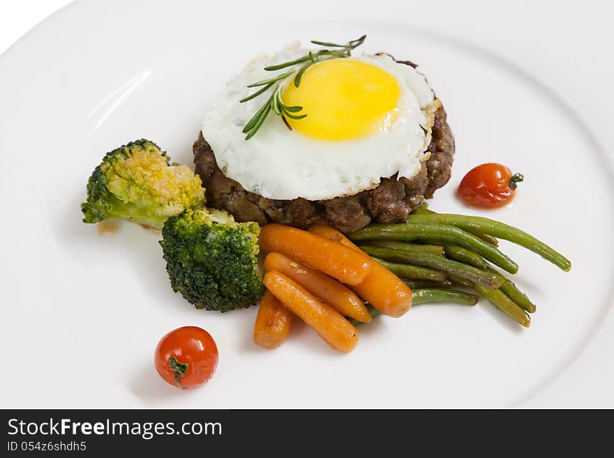 Patty, cooked vegetables and fried eggs