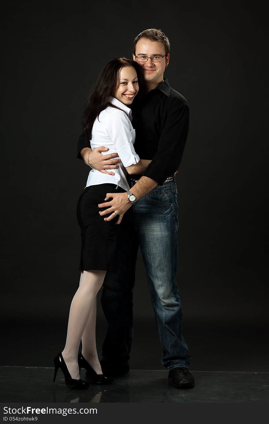 Happy young couple posing in studio on black background