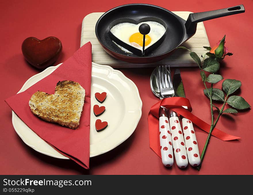 Red theme Valentine breakfast with heart shape egg and toast with love hearts on red background.