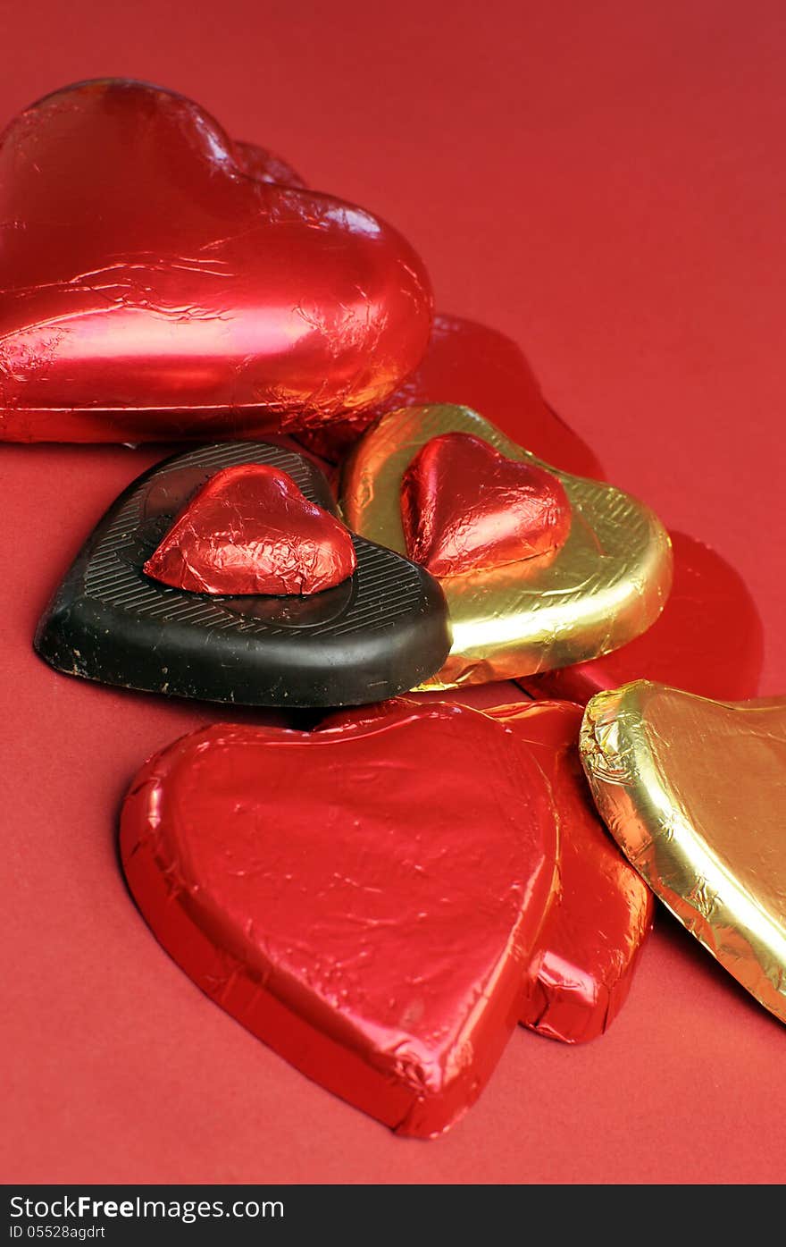 Red and gold wrapped chocolates against a red background for Valentine's Day, Christmas, birthday or someone special. Red and gold wrapped chocolates against a red background for Valentine's Day, Christmas, birthday or someone special.