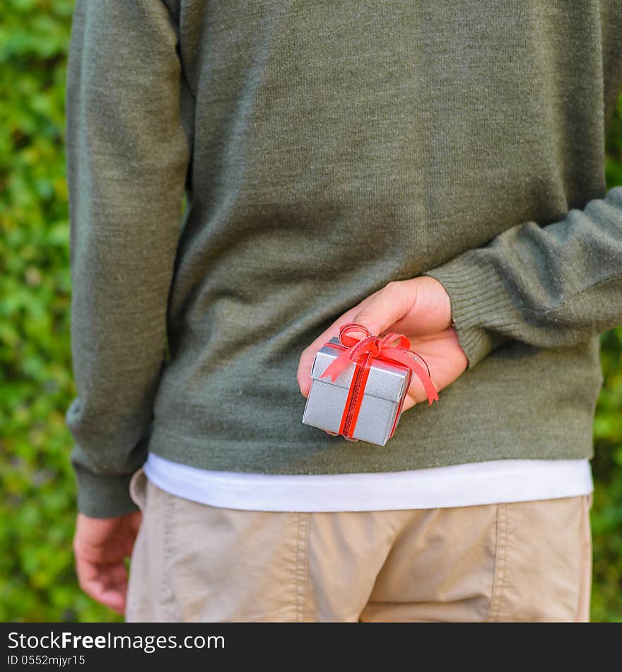 Man hide gift box behind his back