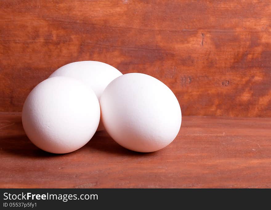 Three white eggs on the wooden background