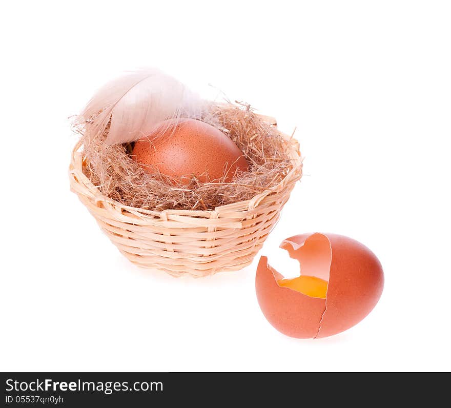 Egg broken on the background of nests with egg and the feather of a bird on the white