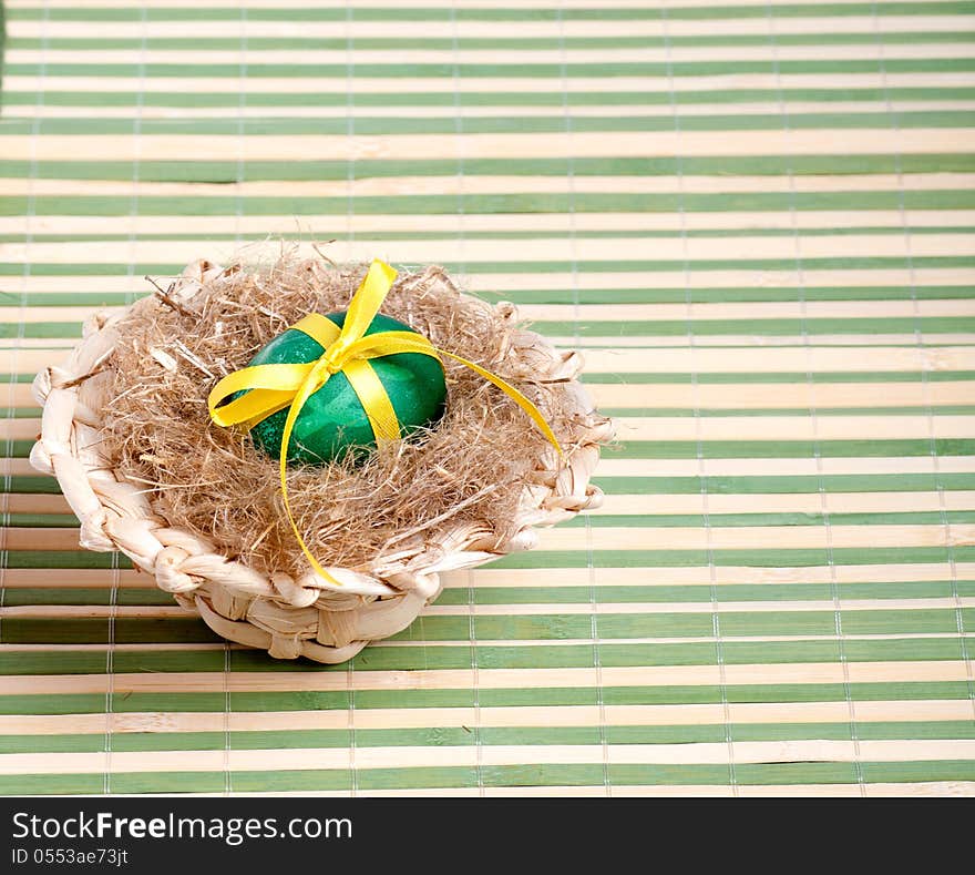 Green Easter egg in a straw hat on the decorative straw