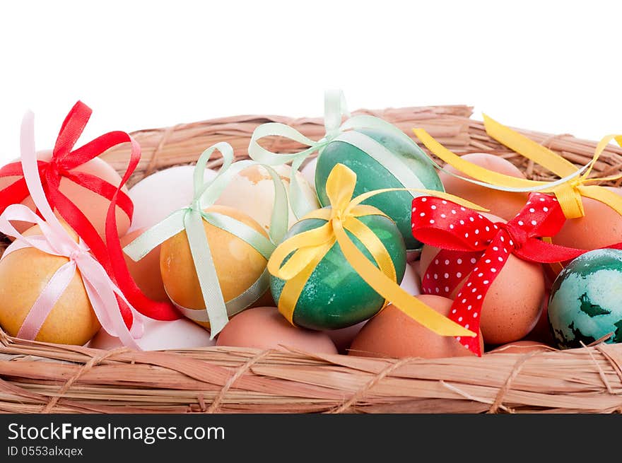 Easter eggs in a straw basket on the white