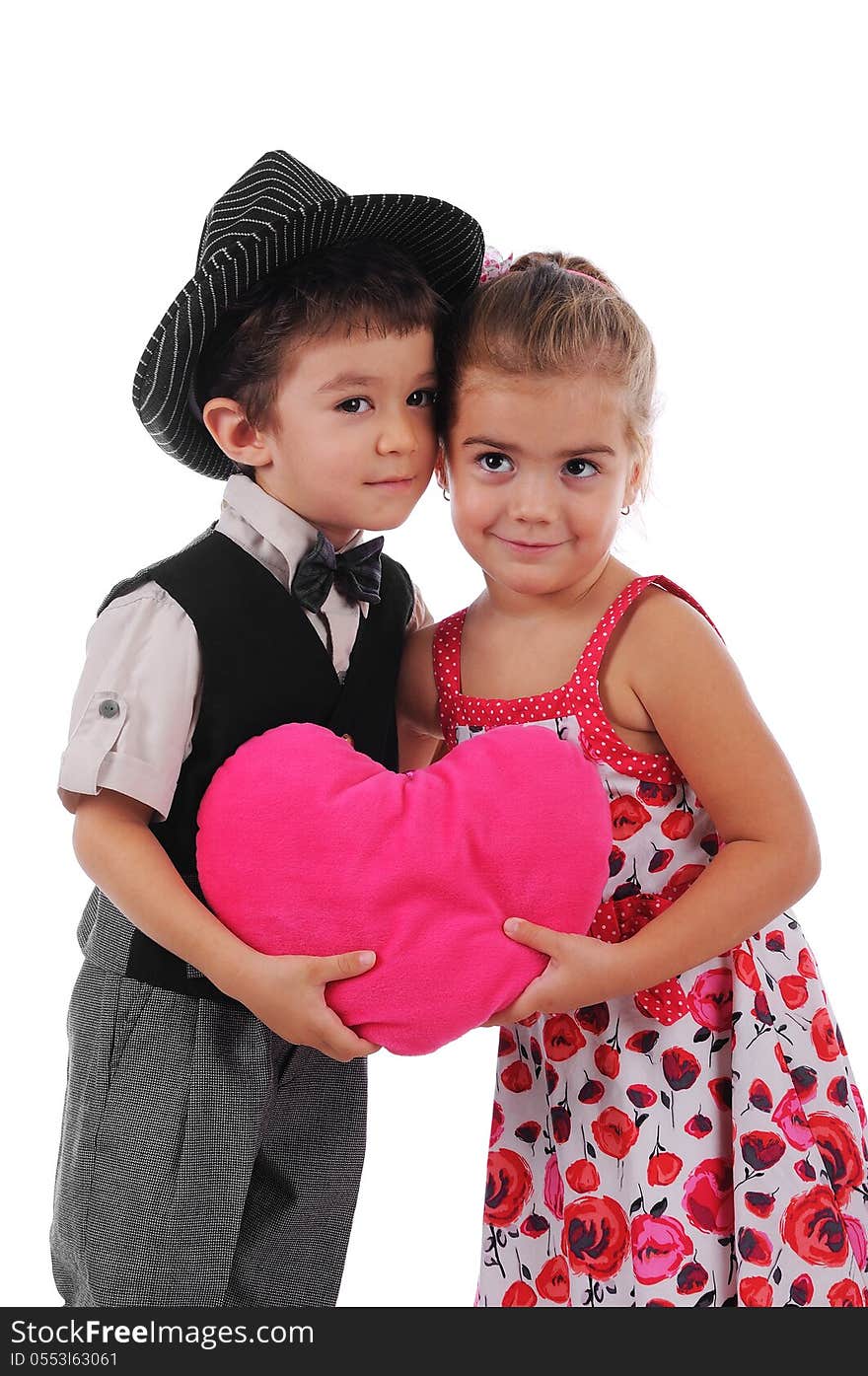 Little boy and girl hug each other and they are holding a big pink heart. Little boy and girl hug each other and they are holding a big pink heart