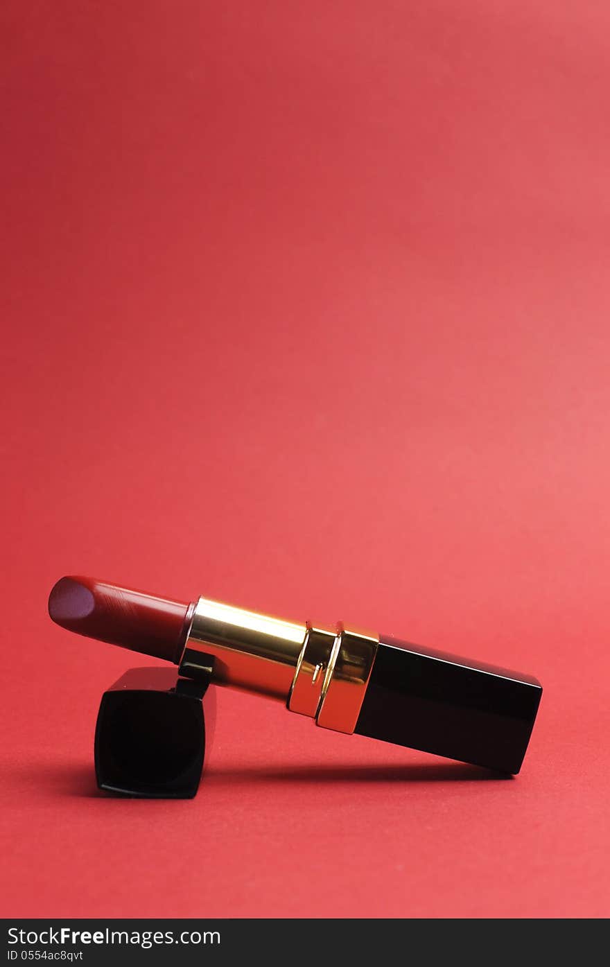 Iconic symbol of femininity, a luxury red lipstick against a red background. Iconic symbol of femininity, a luxury red lipstick against a red background.