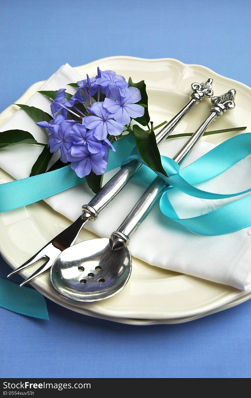 Beautiful silver cutlery, plates and serviette napkins for a modern twist on traditional table setting elegance. Blue theme for Easter or special occasion - vertical. Beautiful silver cutlery, plates and serviette napkins for a modern twist on traditional table setting elegance. Blue theme for Easter or special occasion - vertical.