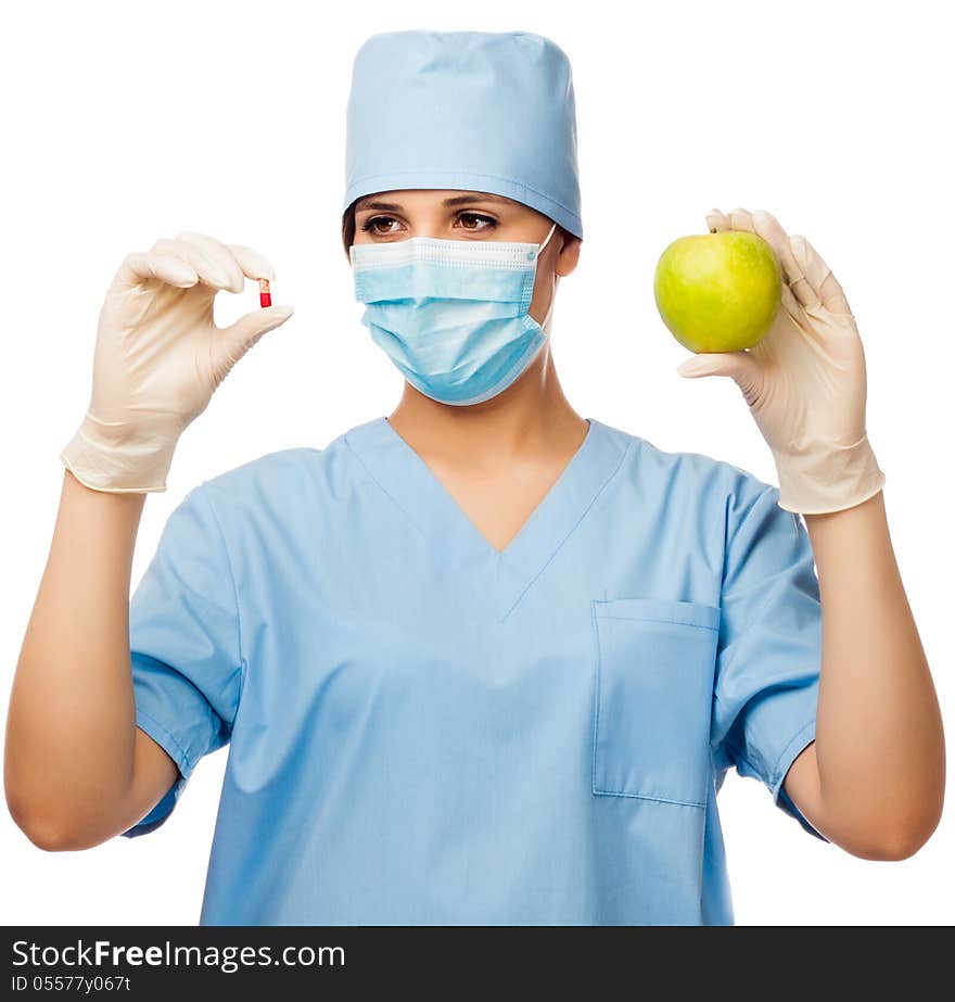 Young doctor holding pill and apple, looking at pill. isolated white background