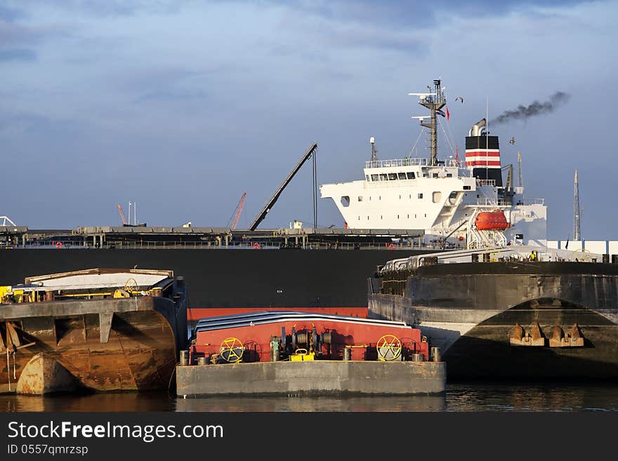 Push barges moored in the port and a bulk carrier in the background in the Port of Rotterdam. Push barges moored in the port and a bulk carrier in the background in the Port of Rotterdam