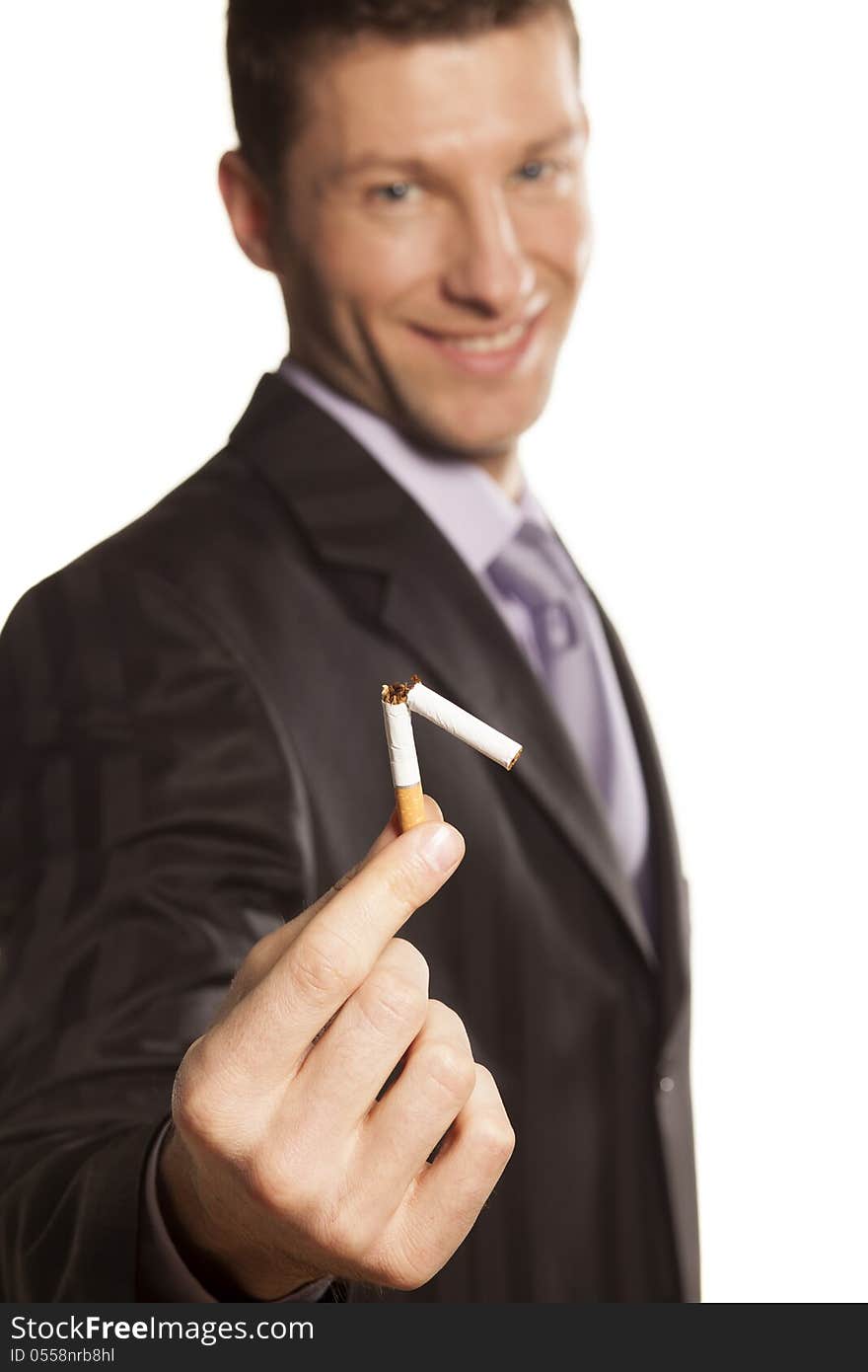 Smiling handsome businessman holding a broken cigarette in his hand on white background. Smiling handsome businessman holding a broken cigarette in his hand on white background