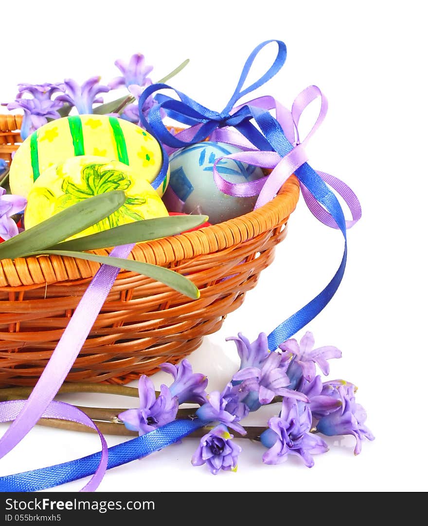 Colorful painted Easter eggs with violet flowers and ribbons in wooden basket. Colorful painted Easter eggs with violet flowers and ribbons in wooden basket