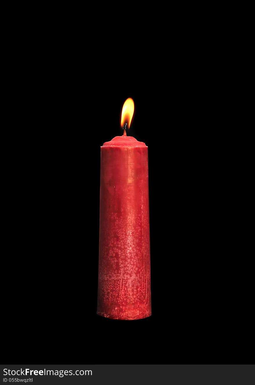 A single burning red candle isolated in front of black background