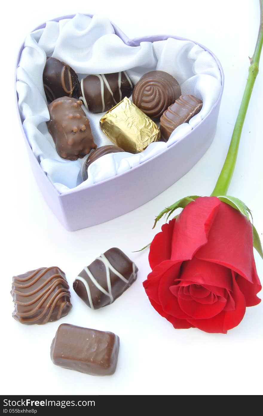 Assortment of chocolates inside a heartshaped box with a card and decorative red ribbon. Assortment of chocolates inside a heartshaped box with a card and decorative red ribbon