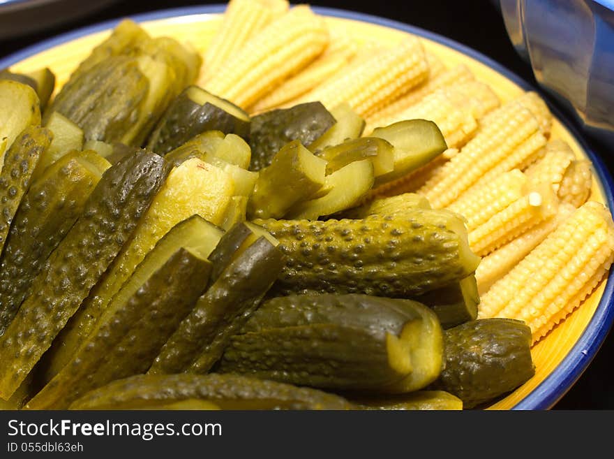 Image of pickles and corn on the plate.