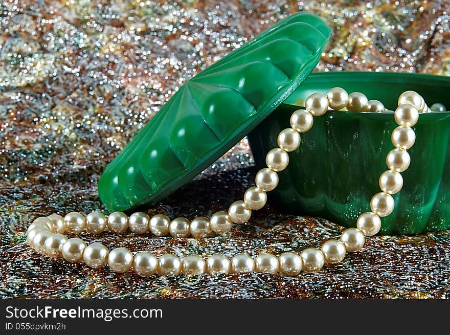 Pearl necklace spanning the green porcelain bowl with cap