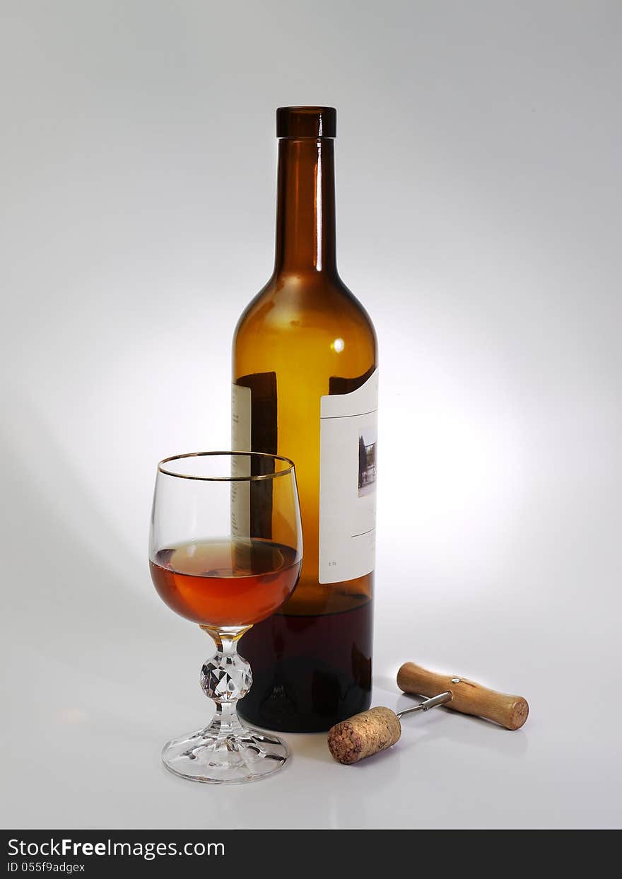 A glass of wine, a bottle, and corkscrew on a gray background