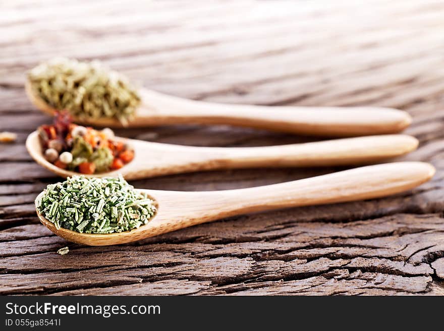 Variety of spices in the spoons on an old wooden table. Variety of spices in the spoons on an old wooden table.