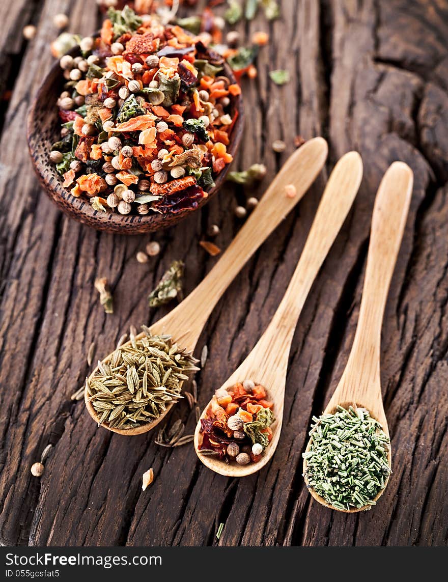 Variety of spices in the spoons on an old wooden table. Variety of spices in the spoons on an old wooden table.