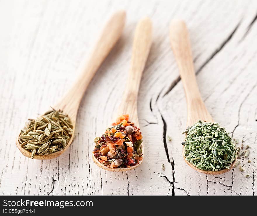 Variety of spices in the spoons on an white old wooden table. Variety of spices in the spoons on an white old wooden table.