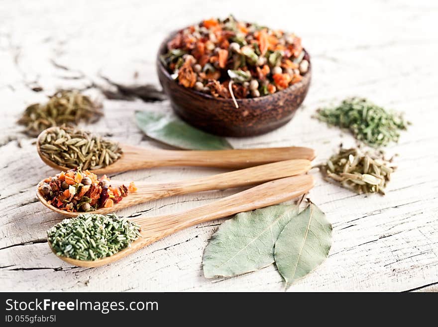 Variety of spices in the spoons on an white old wooden table. Variety of spices in the spoons on an white old wooden table.