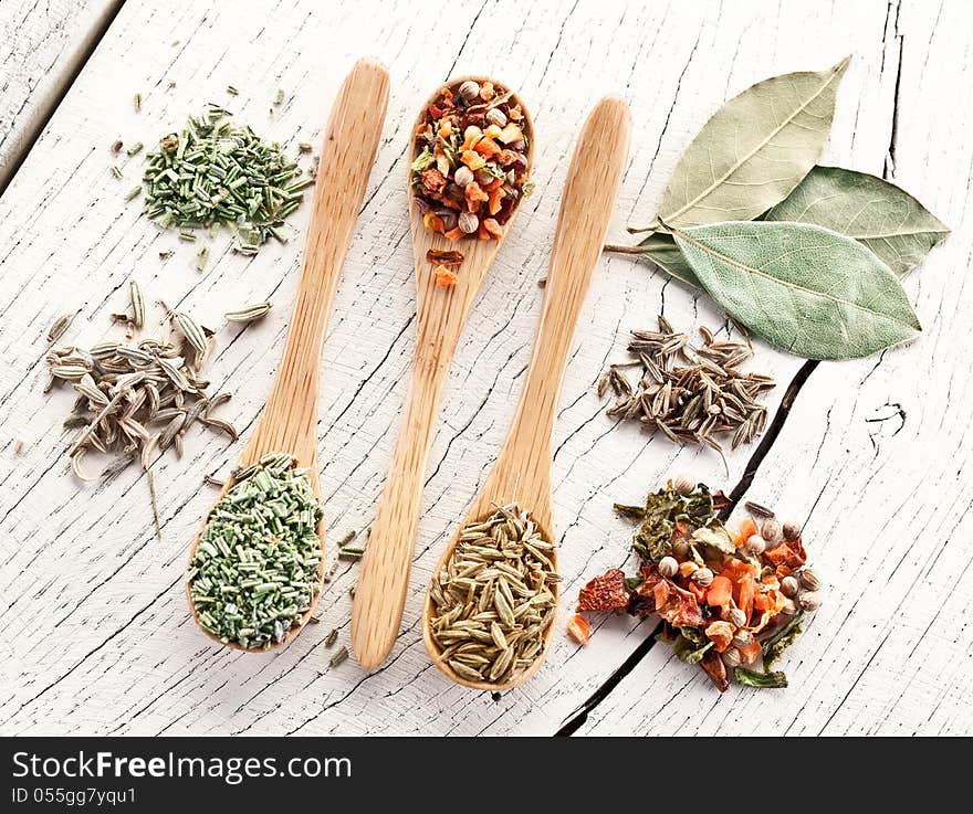 Variety of spices in the spoons on an white old wooden table. Variety of spices in the spoons on an white old wooden table.