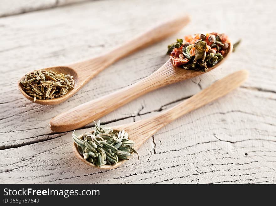 Variety of spices in the spoons on an white old wooden table. Variety of spices in the spoons on an white old wooden table.