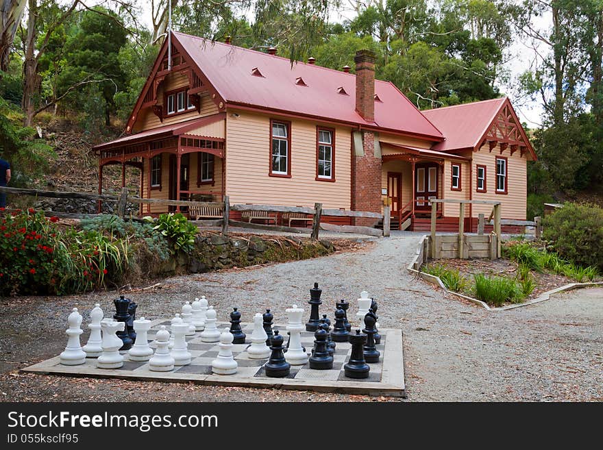 A large chess set sits before a cottage at Coal Creek, Korumburra, Australia. This cottage was formerly a court house in pioneering days. A large chess set sits before a cottage at Coal Creek, Korumburra, Australia. This cottage was formerly a court house in pioneering days.