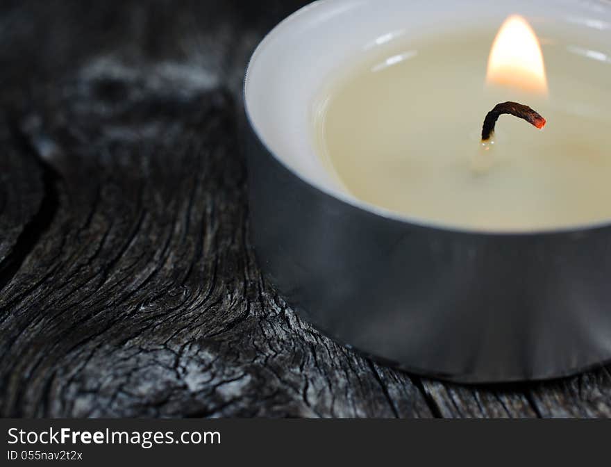 Close-up Photograph Of A Lit Tea Light Candle On An Old Wooden B