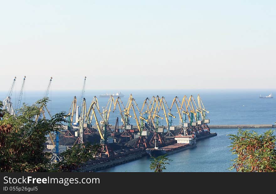 Port berth with material handling equipment and cargo ships at anchor. Port berth with material handling equipment and cargo ships at anchor