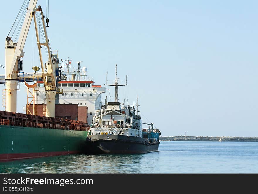 Port berth with material handling equipment and cargo ships at anchor. Port berth with material handling equipment and cargo ships at anchor