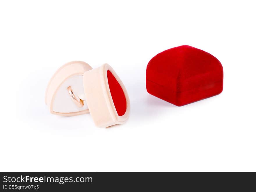 Simple gold ring displayed in a romantic heart shaped jewelry box lying on its side alongside a closed square red jewelry box on a white background. Simple gold ring displayed in a romantic heart shaped jewelry box lying on its side alongside a closed square red jewelry box on a white background.