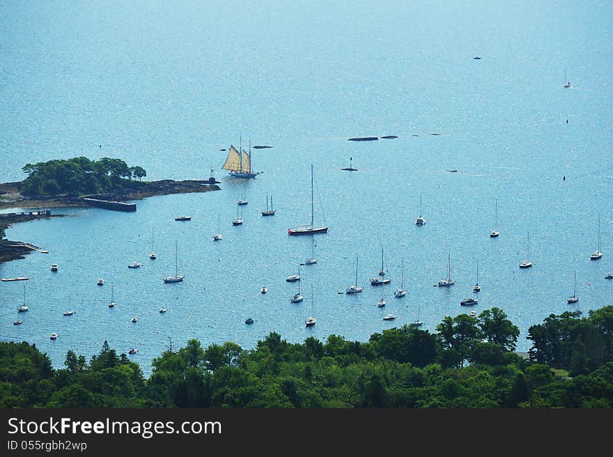 Multi-sailed clipper ship coming into the safety of a harbor as seen from a mountain top. Multi-sailed clipper ship coming into the safety of a harbor as seen from a mountain top