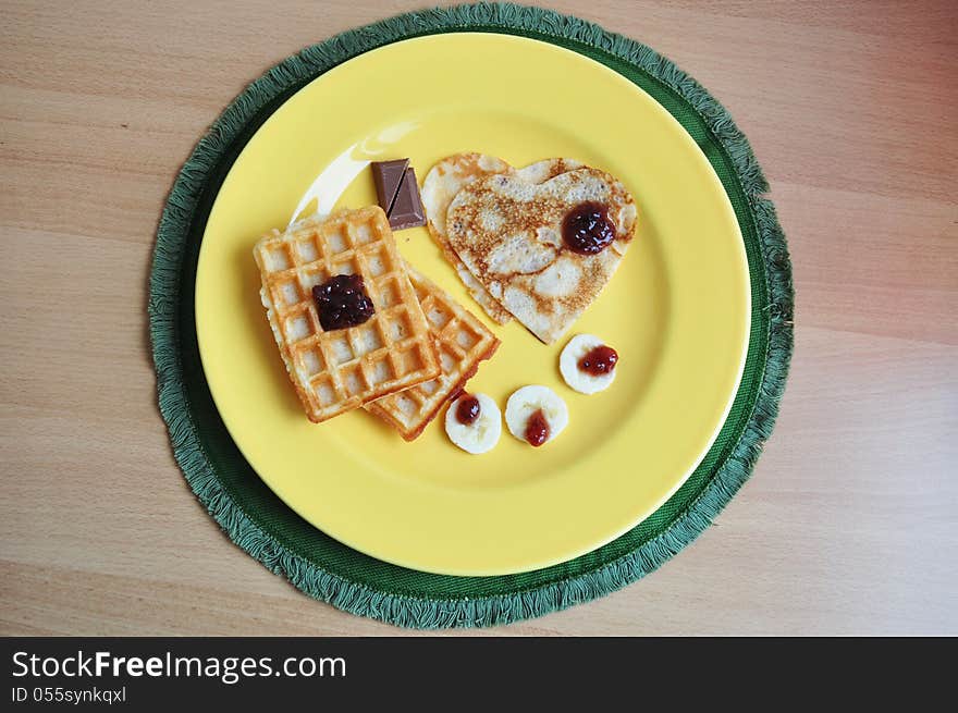 Heart-shaped pancakes and waffle with banana and raspberry jam. A perfect breakfast for Valentine's Day.