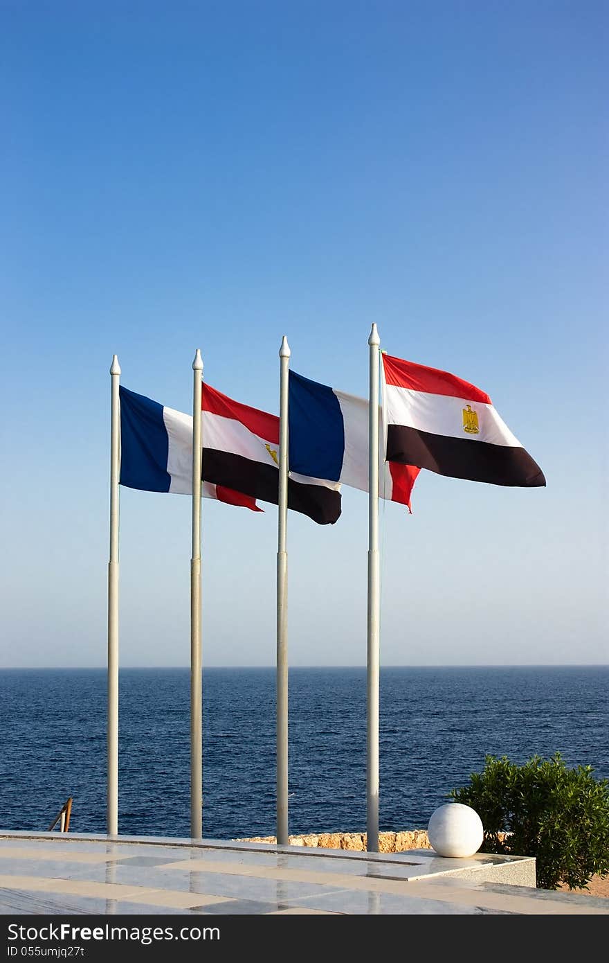 French and Egyptian flags flies in the wind on the blue sea on the background of the clear sky under sunlight. French and Egyptian flags flies in the wind on the blue sea on the background of the clear sky under sunlight