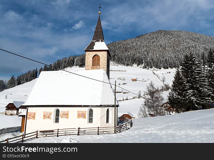 A wintertime view of a small church with a tall steeple