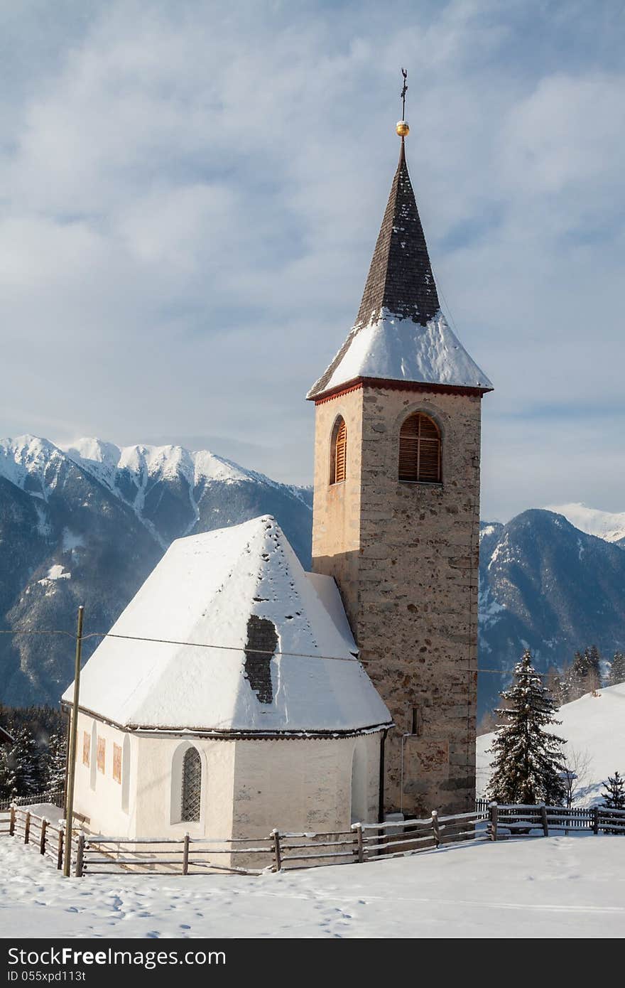 A wintertime view of a small church with a tall steeple